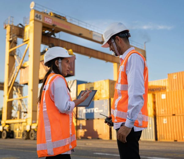 Deux inspecteurs QHSE en casque et gilet, tablette en main, sur un site industriel